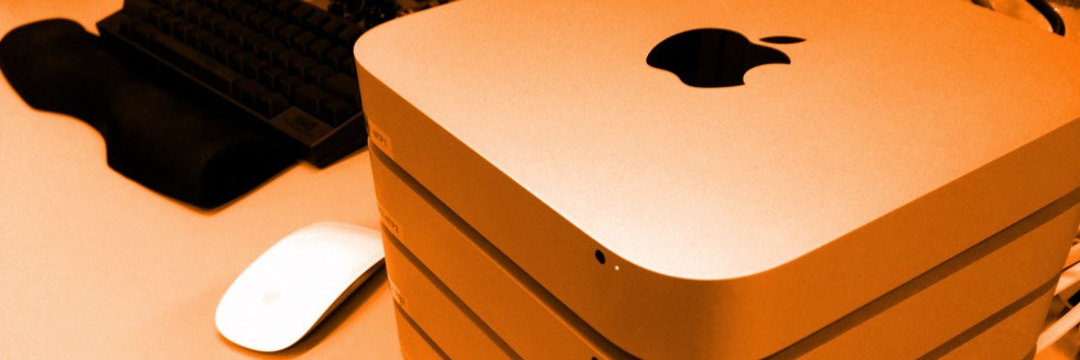 An evocative sepia-toned photo of a stack of Mac mini computers, and a low profile Apple Magic Mouse