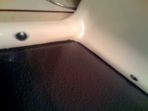 A picture of the back corner of a glass top oven range. There are chips in the white enamel border around the range top