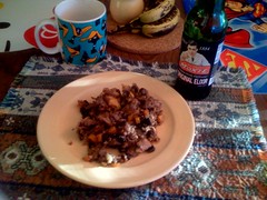 A photo of a table with a pale yellow plate with turkey hash piled on it. A bottle of Moxie soda sits beside the plate.